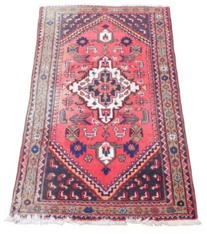 A Shiraz red ground rug, the central field with a floral medallion, birds and flowers, within borders of repeating flowers and dog tooth decoration, 153cm x 95.5cm.