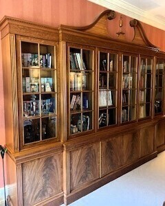 A 20thC mahogany breakfront library bookcase, with a dentil moulded swan neck pediment, and central turned urn, above six astragal glazed doors, enclosing shelves, raised on a base with six cupboard doors, above a plinth, 274cm high, 362cm wide, 51.5cm de