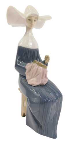 A Lladro porcelain figure, modelled as a seated nun completing needlepoint, printed marks, 21cm high.