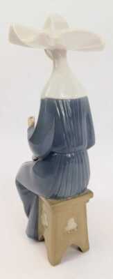 A Lladro porcelain figure, modelled as a seated nun completing needlepoint, printed marks, 21cm high. - 2