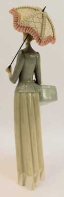 A Lladro porcelain figure, modelled as a lady holding a parasol and box, printed marks, 37cm high. - 2