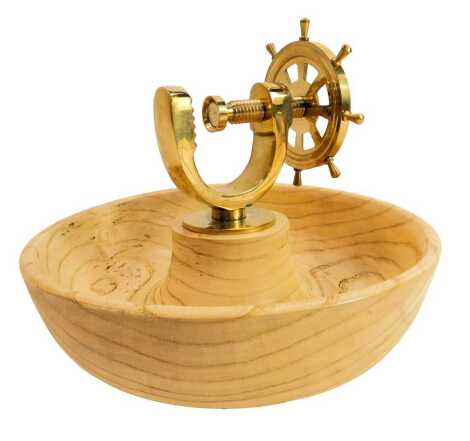 A brass ship's wheel nut cracker, mounted on a circular wooden base, 22cm diameter.