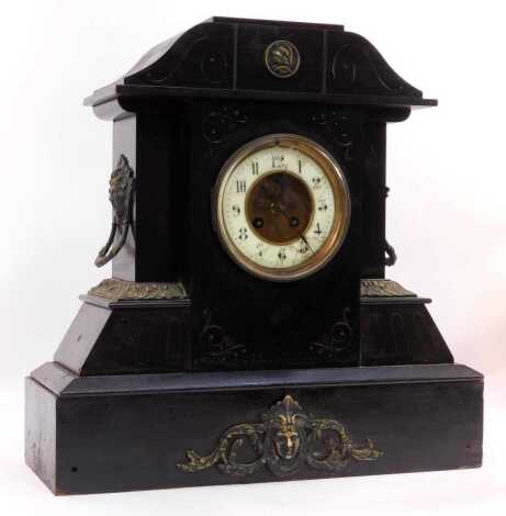 A Victorian black slate mantel clock, the circular white enamel dial bearing Arabic numerals, with visible brocot escapement, eight-day movement, with coil strike, the case of architectural form with mask ring handles, 45cm high.