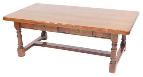 A 20thC oak coffee table, the rectangular top with a rounded edge with two frieze drawers, on cylindrical turned supports with a H shaped stretcher, 45cm high, the top 129cm x 69cm.