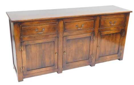 A 20thC oak sideboard, the rectangular top above three drawers with three panelled cupboards to base, on stiles, 81cm high, 165cm wide, 45.5cm deep.