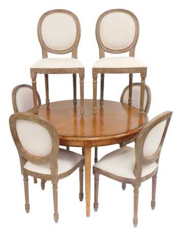 A set of six 20thC limed oak balloon back dining chairs, each with an overstuffed seat and back, in cream upholstery, on cylindrical reeded legs with flower head roundel carving to the top of each leg.