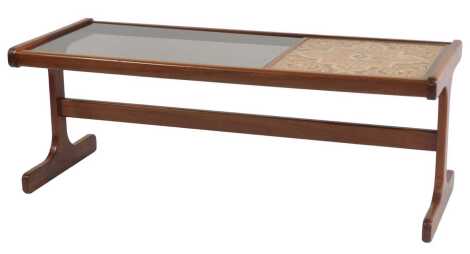 A 1970s teak coffee table, with a smoked glass top beside a tiled section, on shaped end supports united by stretcher, 44cm high, the top 49cm x 120cm.