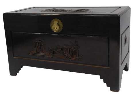 An Eastern camphor wood chest, the hinged lid enclosing a vacant interior with a brass lockplate, the front bearing carving depicting figures, pagoda, etc., on bracket feet, 59cm high, 103cm wide, 50cm deep.