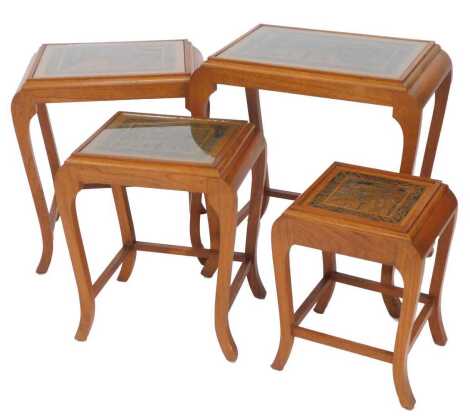 A nest of four Oriental hardwood tables, each top carved with figures, trees, pagoda, etc., on cabriole legs, united by stretchers, the largest 65cm high, the top 54cm x 36cm.