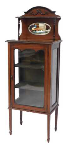 An Edwardian mahogany and line inlaid display cabinet, the shaped top with bow and swag decoration, with upper shelf and turned columns, circular mirror back, the base with a shaped glass door enclosing three shelves, on square tapering legs with spade fe