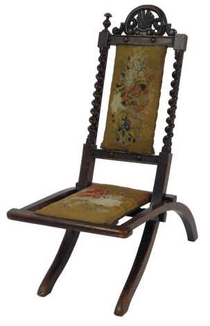 A Victorian mahogany folding chair, with pierced scroll and shell carved back, with barley twist supports, a floral tapestry upholstered seat and back, on out swept legs.