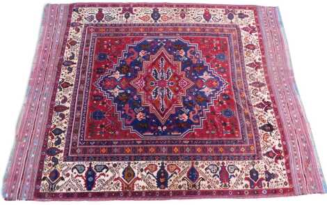 A Turkish red ground carpet, with blue medallions, 335cm x 424cm.