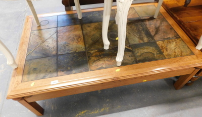 A pine and tile topped coffee table, the multicoloured slate top, on stiles.