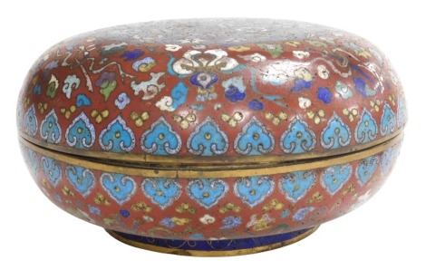 A 19thC Chinese circular compressed cloisonne enamel box, decorated with emblems of flowers and precious objects, on a red ground, the cover with central panel of butterflies and flower heads in polychrome enamels, on blue ground, 11cm high, 24cm diameter