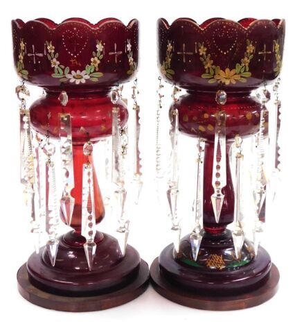 A pair of late 19thC ruby glass lustres, with floral enamel decoration, and prismatic cut glass drops, raised on wooden bases, 37.5cm high. (AF)