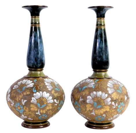 A pair of Doulton Lambeth stoneware vases, of bottle form, the neck decorated in a band of mottled blue and green decoration, gilt heightened, the base decorated with impressed and overpainted flowers, on circular foot, impressed marks No. 197, 26.5cm hig