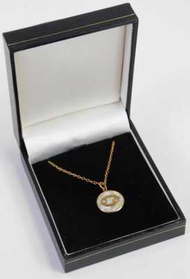 A mother of pearl pendant and chain, the circular mother of pearl with raised yellow metal detail, 1.5cm wide, on a fine link neck chain with barrel clasp, stamped 9ct, 40cm long, 4g. - 4