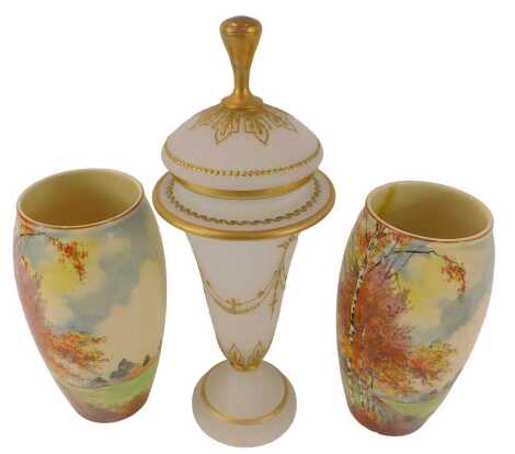 A pair of Royal Doulton pottery vases, of cylindrical tapering form, decorated with autumnal trees, printed marks, 23cm high, (AF), together with a Victorian frosted glass jar and cover, with gilt heightened decoration, 36cm high. (3)