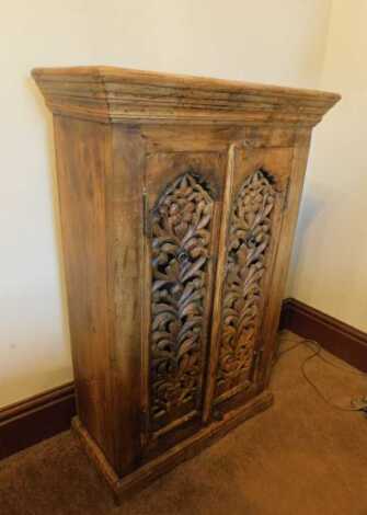 An Eastern hardwood cabinet, with two pierced cupboard doors, on a plinth base, 100cm high, 63cm wide, 30cm deep. This lot is located offsite. For further details and to arrange a viewing, please call The Bourne Auction Rooms on 01778 422686.