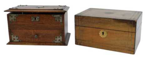 An early 20thC oak work box, with metal mounts and shield cartouche, the hinged lid enclosing a vacant interior, with a lower drawer, 16cm high, 27cm wide, 18cm deep, together with a mahogany and brass inlaid work box, the hinged lid enclosing a vacant in