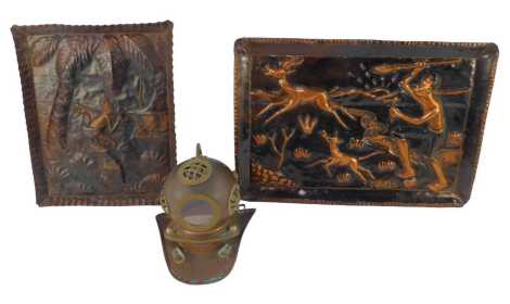 African School. Two embossed copper plaques, one depicting a figure hunting antelope, 33cm x 47cm, another depicting a figure walking before a palm tree and building, 37cm x 30cm, together with a brass and copper diving helmet, 18cm high.