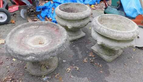 A pair of composition stone garden urns, each of circular form with animal mask and leaf decoration, on square pedestal base, 36cm high, together with a composition stone birdbath, 27cm high.