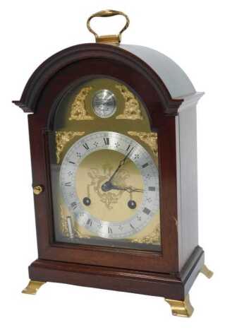 A mahogany cased mantel clock, the brass dial with silvered chapter ring bearing Roman and Arabic numerals for Comitti of London, eight day movement, the dial decorated with mask and scroll spandrels, the case with a brass carrying handle on brass bracket