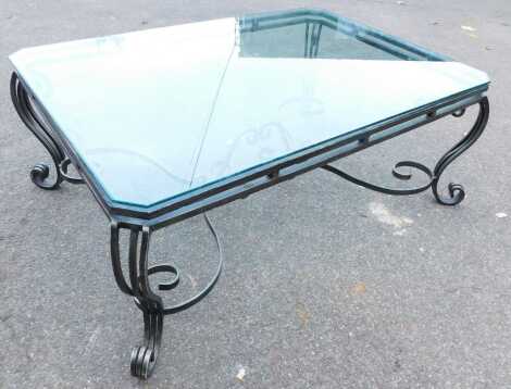 A contemporary glass and wrought metal coffee table, the rectangular top with canted corners, on a wrought iron scroll work base, 53.5cm high, the top 92cm x 133cm.