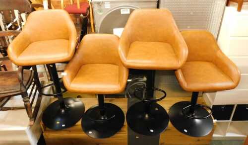 A set of four brown faux leather upholstered bar stools, each on a black metal base, with footrest.