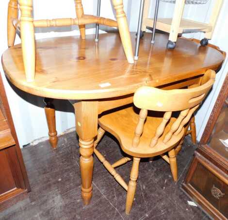 A pine kitchen table, the lozenge shaped top raised on turned legs, 77cm high, the top 75cm x 116cm, together with four dining chairs.