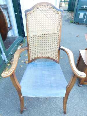 An early 20thC mahogany framed armchair, with caned back, scrolling arms, solid upholstered seat, on square legs.