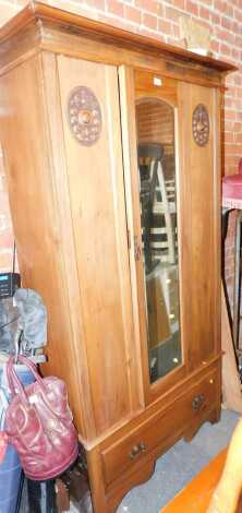 A 20thC walnut single wardrobe, the top with a moulded edge above a glazed central door flanked by two carved roundels, the base with a single drawer, on bracket feet, 194cm high, 97cm wide, 44cm deep.