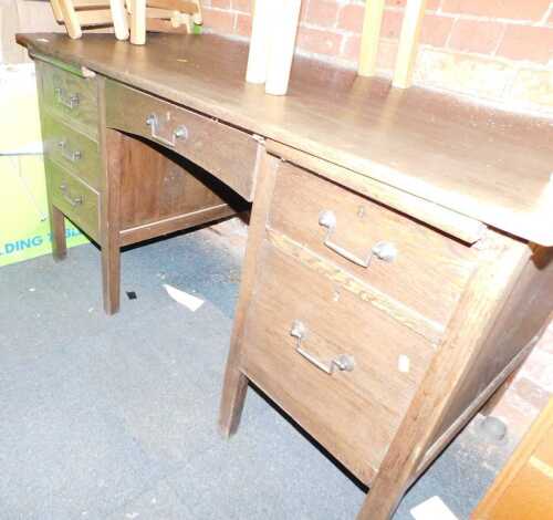 A 20thC oak desk, the rectangular top, above an arrangement of six drawers, on square legs, 75cm high, 138cm wide, 76.5cm deep.