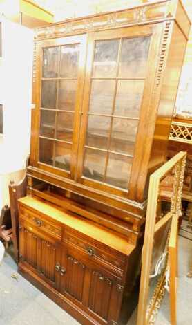 An oak Old Charm style side cabinet, with two carved drawers above two carved cabinets, on a plinth, 69cm high, 91cm wide, 44cm deep, together with an oak cabinet, with panelled glazed doors. (2)