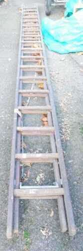 A wooden extending ladder, extended length approx 26ft.