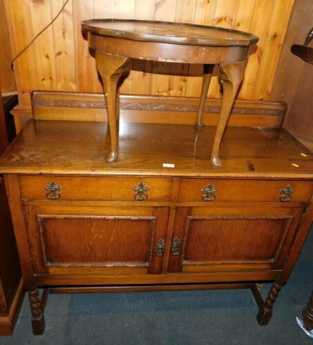 A 20thC oak sideboard, the top with a raised carved back, the base with two drawers above two carved panelled doors, on barley twist legs united by H shaped stretcher, 103cm high, 120cm wide, 47cm deep, together with an oak occasional table.