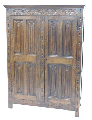 An 18thC style oak cupboard, with Arabesque and linenfold carving, 184cm high, 142cm wide, 48cm deep.