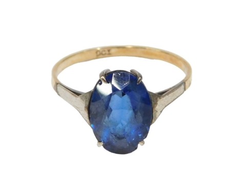 A blue stone set dress ring, the oval blue paste stone, claw set, on white metal shoulders, on a yellow metal band stamped 9ct, ring size O½, 1.8g all in.