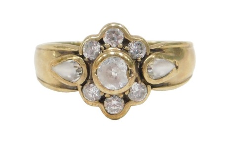 A CZ floral cluster ring, the central cluster set with seven CZ stones, flanked by two teardrop cut CZs to shoulders, on yellow metal band stamped 375, ring size O½, 3.6g all in.