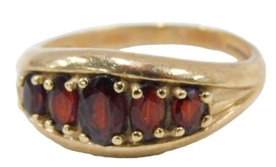 A 9ct gold garnet dress ring, set with five oval cut garnets, each claw set, on plain band, ring size R, 3.9g all in.