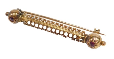 A Victorian bar brooch, the central bar set with seed pearls, with two rubies to each end, formed as an orb, yellow metal unmarked, 5cm wide, in William Hope of Hexham box.