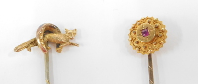 Two stick pins, comprising a horse's hoof and fox topped stick pin, unmarked, and a cluster set with central ruby and yellow metal, unmarked, 2.3g all in, both partially boxed. (2) - 2