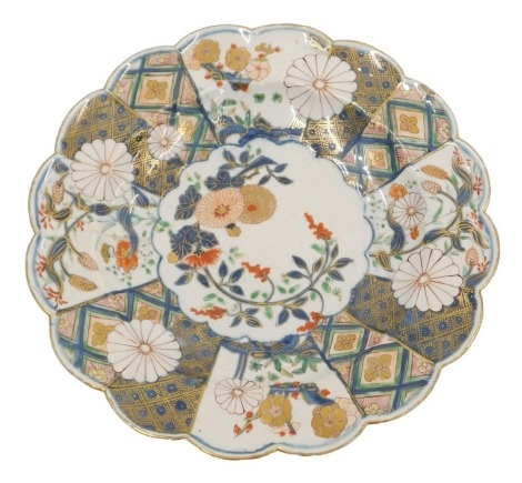 A 19thC Japanese Imari plate, decorated with flowers, leaves, etc., within a petalated border, 24cm diameter. (AF)