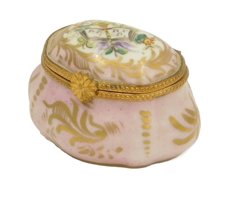 A French porcelain trinket box, on a pink ground decorated with trumpet and books, marked Made in France, 6cm high.