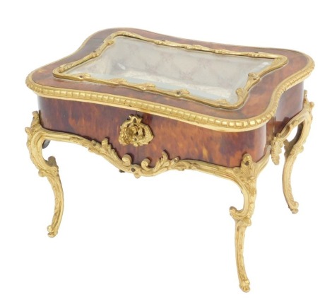 A late 19th/early 20thC French tortoiseshell and gilt metal jewellery case, modelled in the form of a display table, the shaped top with a central bevelled glass enclosing a padded interior, on cabriole legs, 23cm wide.