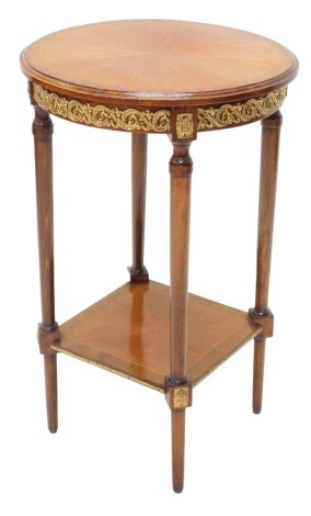 An early 20thC French mahogany and gilt metal occasional table, the circular top with a cross banded border, above a gilt metal edge, on turned supports with square under tier and tapering feet, 73cm high, 44cm wide.