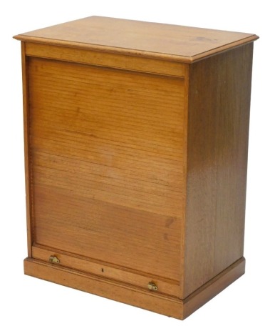 An early to mid 20thC oak stationary cabinet, the rectangular top with a moulded edge above a tambour door revealing various pigeon holes, on a plinth, 83cm high, 68cm wide.