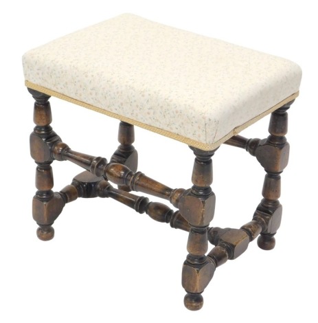 An oak stool, with a padded top, on turned legs and stretchers, 50cm wide.