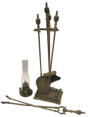 A 20thC brass fire side set, comprising brush, poker, tongs, and shovel, in a fitted basket, 78cm high, and a wall mounted oil lamp, 36cm high. (2)