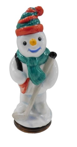 A Halcyon Days enamel snowman pill box, depicting snowman with hockey stick, 9cm high, boxed.